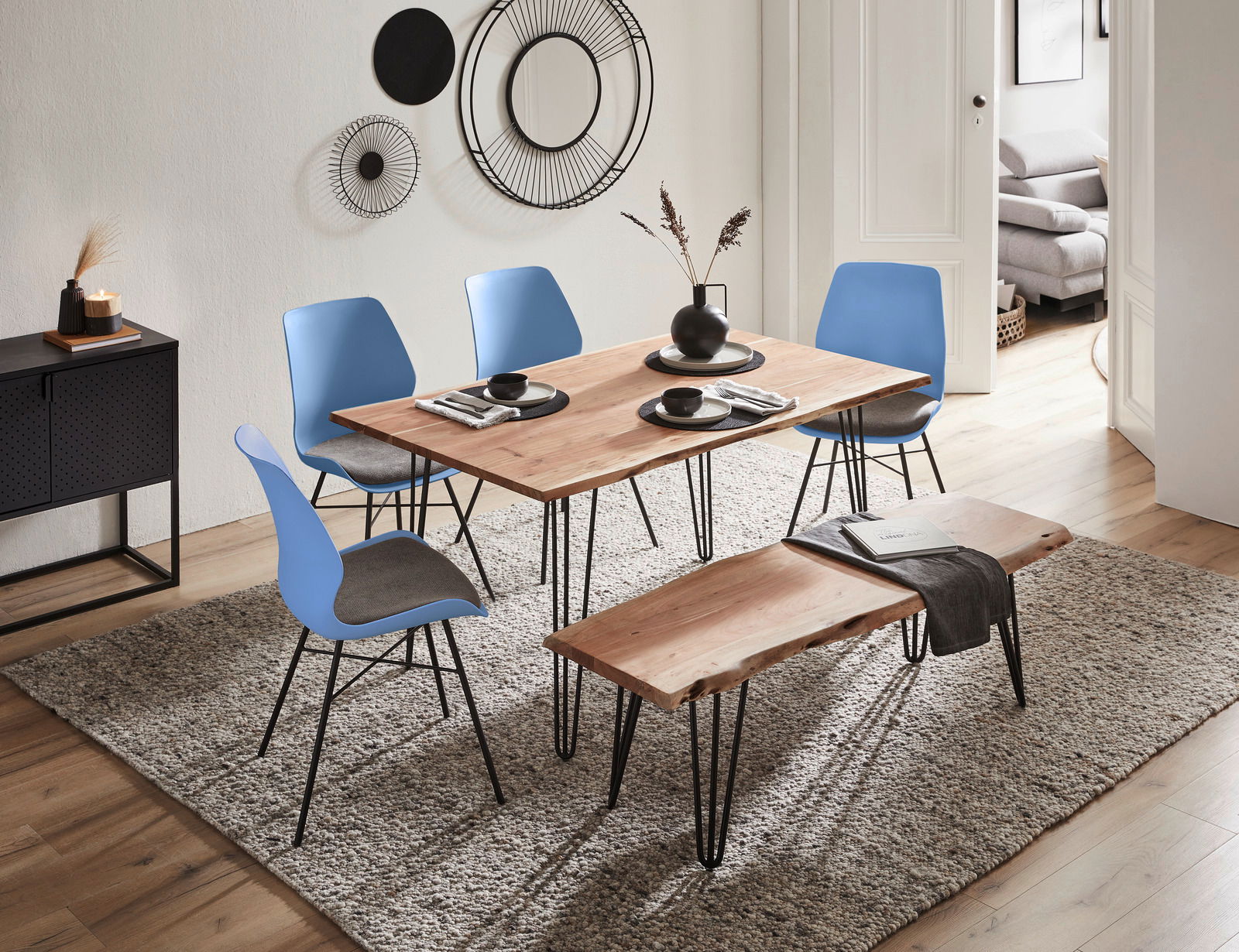 Esszimmer mit modernem Holztisch, blauen Stühlen und Bank auf Teppich, seitliche Perspektive