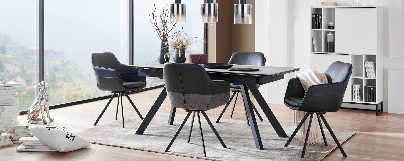 Esszimmer mit modernem Tisch und vier schwarzen Sesseln, seitliche Perspektive