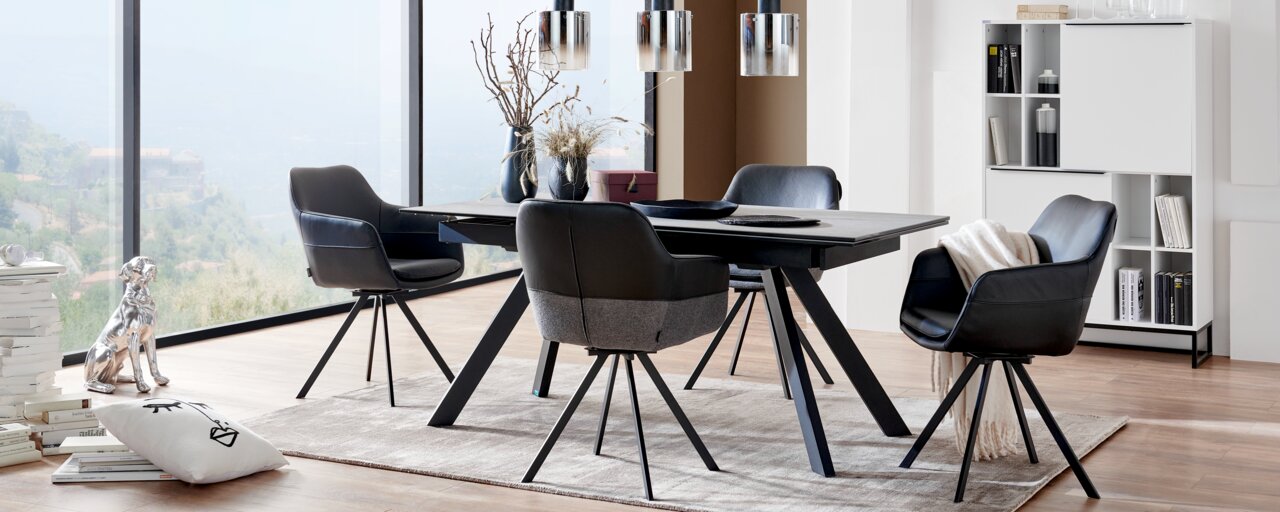 Esszimmer mit modernem Tisch und vier schwarzen Sesseln, seitliche Perspektive
