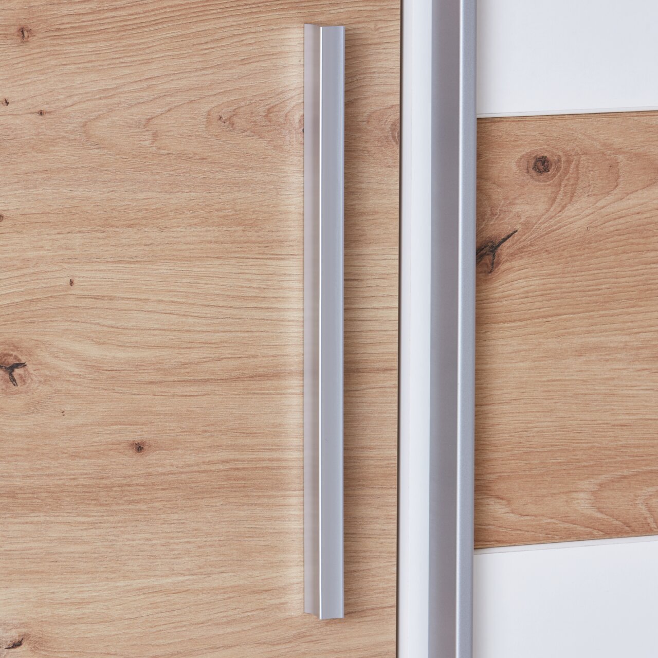 Close-up van een draai-schuifdeurkast met houtlook en zilveren handgrepen, zijaanzicht