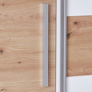 Close-up van een draai-schuifdeurkast met houtlook en zilveren handgrepen, zijaanzicht