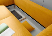 Blick von oben auf ein gelbes Funktionssofa mit Stauraum, in dem ein graues Kissen und ein gelbes Kissen liegen.