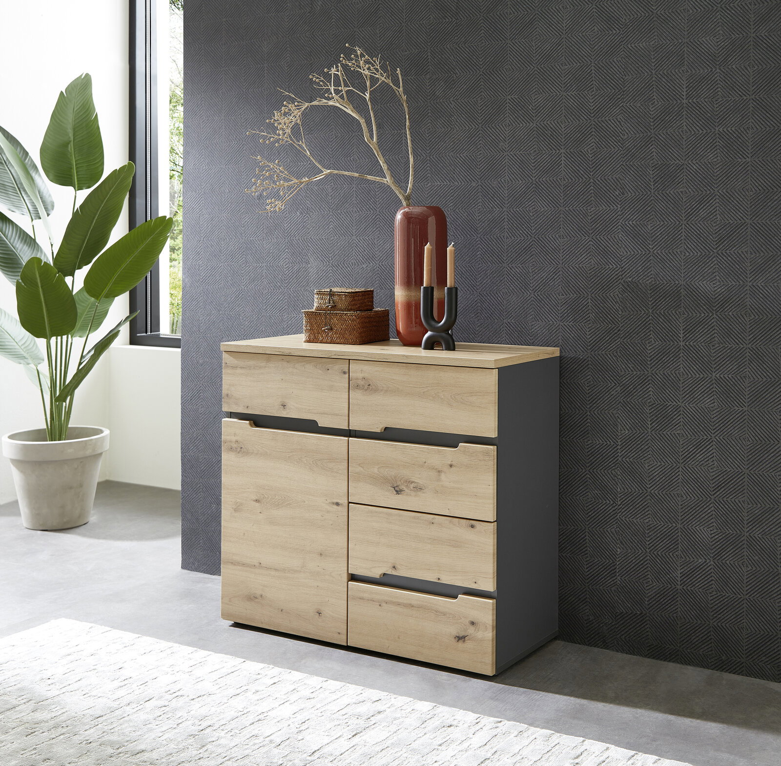 Moderne Kommode aus Holz mit vier Schubladen und zwei Türen, dekoriert mit Vasen und Körben, seitliche Perspektive