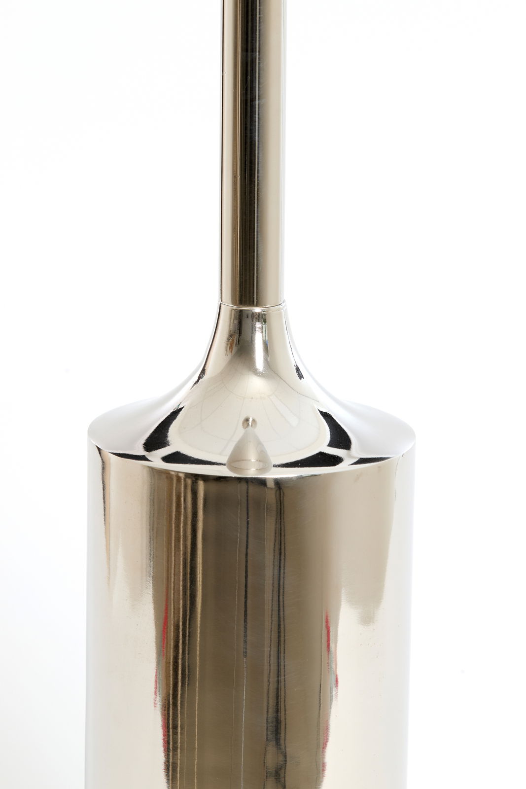 Nahaufnahme eines glänzenden, metallischen Kerzenhalters in zylindrischer Form, fotografiert aus der Seitenperspektive.