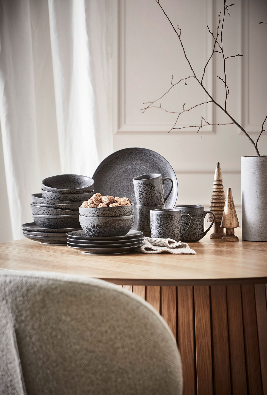 Kombiservice 20-teilig in dunklem Design, bestehend aus Tellern, Schalen und Tassen, auf einem Holztisch arrangiert. Seitliche Perspektive.