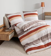 Bettwäsche-Set 155x220cm mit Streifenmuster in warmen Tönen, auf einem Bett mit Holzrahmen und Nachttisch, seitliche Perspektive