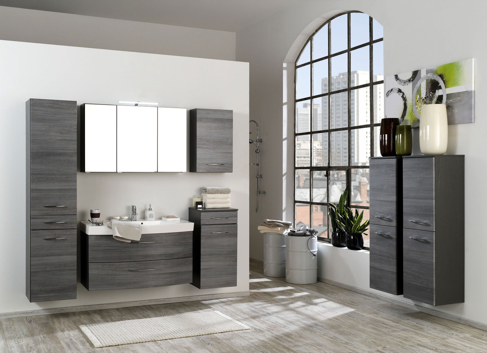 Moderne Badezimmermöbel in dunklem Holzdekor, bestehend aus Hochschränken und einem Waschtisch, in einer stilvollen Raumansicht mit großem Fenster im Hintergrund.