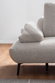 Nahaufnahme einer modernen, grauen Rundecke mit verstellbarer Armlehne, auf einem Holzboden stehend, von der Seite betrachtet.