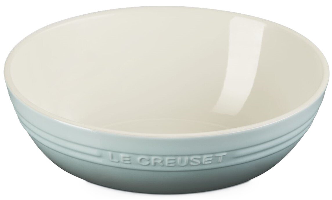 Hellblaue Le Creuset Keramikschale mit cremeweißem Innenraum, freigestellt vor weißem Hintergrund, in seitlicher Frontansicht leicht von oben