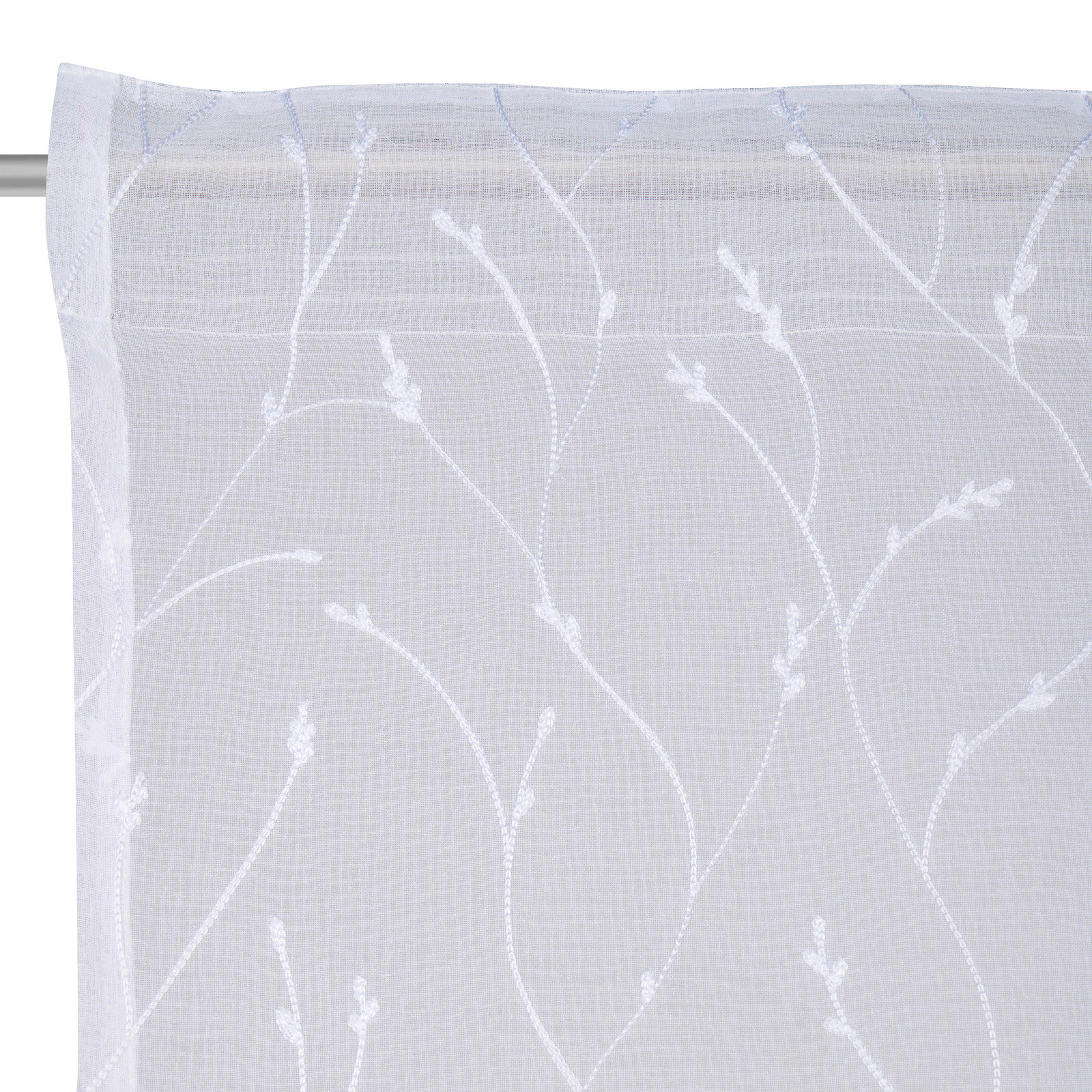 Nahaufnahme eines weißen Fertigvorhangs mit zartem, floralem Muster auf einer Gardinenstange.