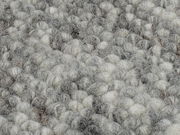 Nahaufnahme eines handgewebten Teppichs mit grauen und weißen Wollschlingen.