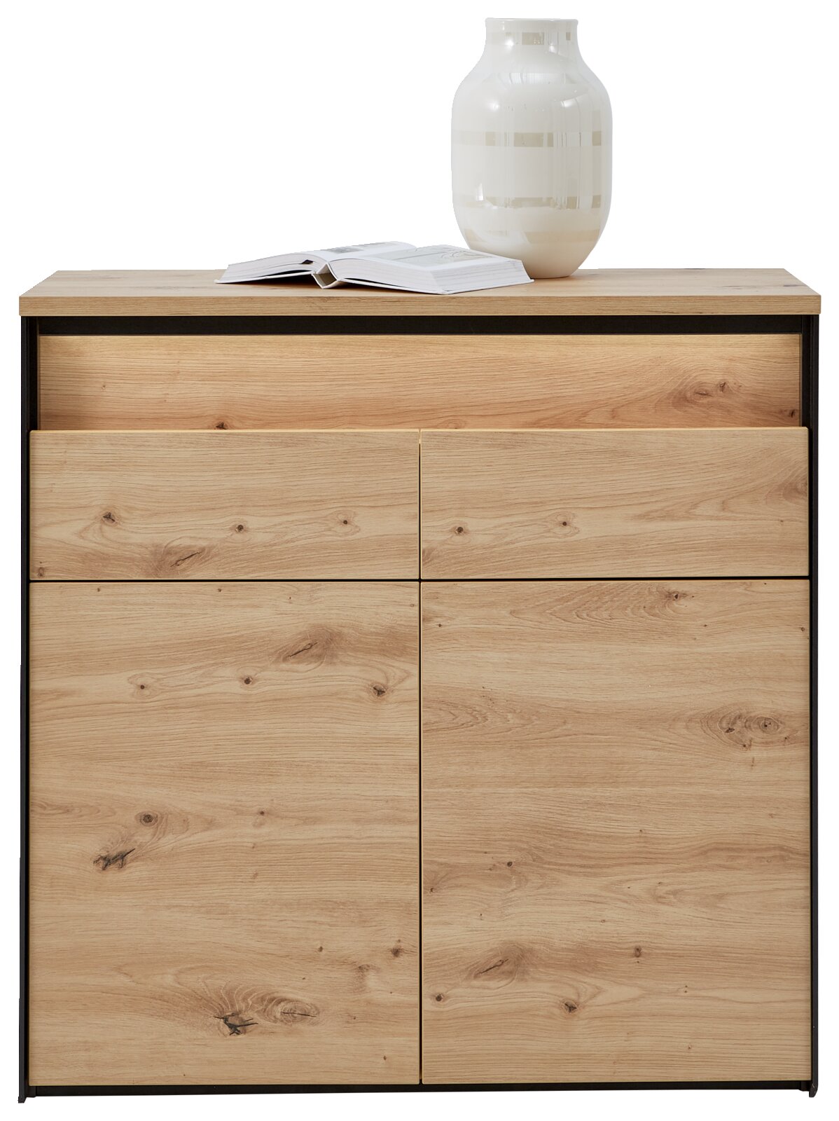 Commode van licht hout met twee lades en twee deuren, met daarop een open tijdschrift en een witte vaas, gezien van voren.