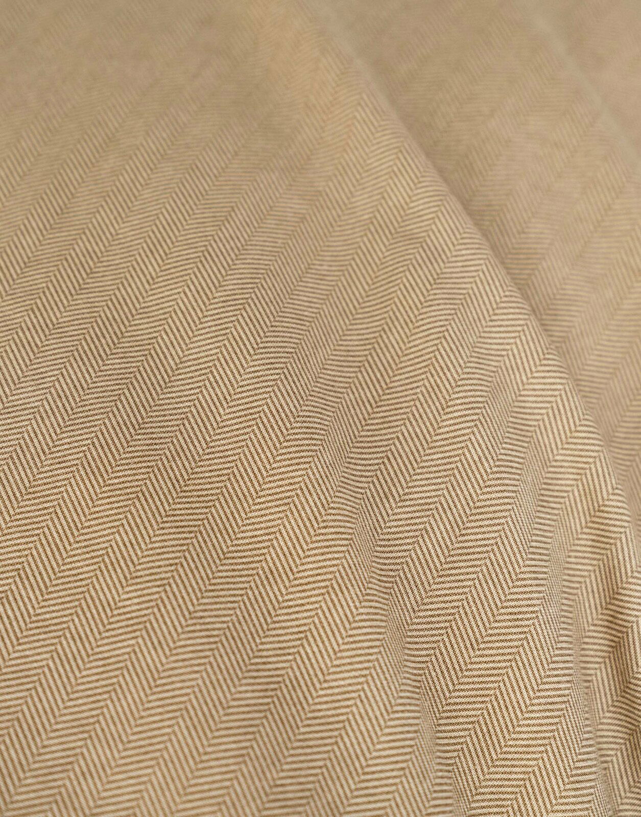 Nahaufnahme einer Bettwäsche mit Fischgrätenmuster in Beige.