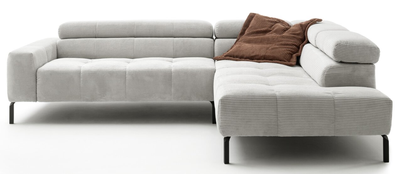 Graues Ecksofa mit geripptem Stoffbezug und schwarzen Beinen, von vorne betrachtet. Ein braunes Kissen liegt auf der rechten Seite.