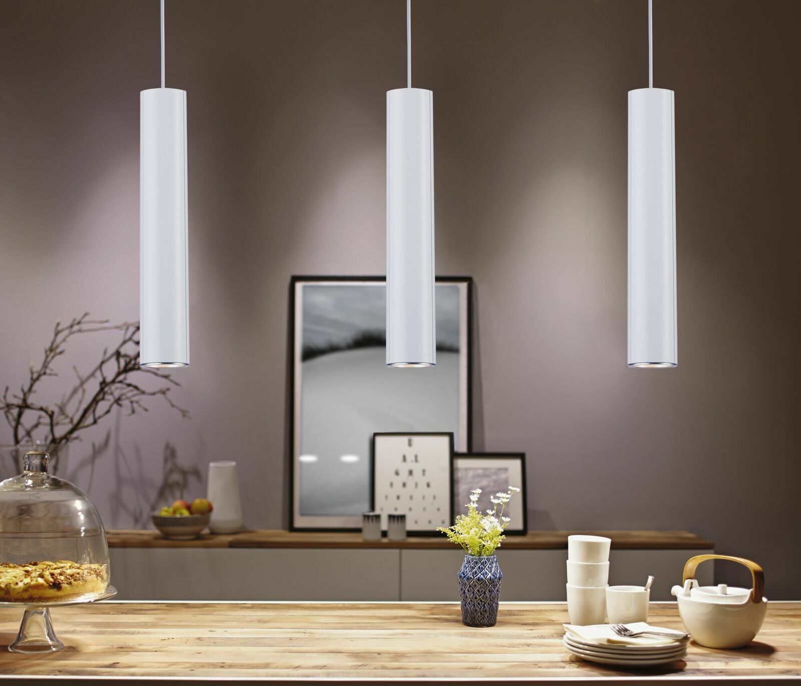 PAULMANN Schienenpendel Catalejo URAIL Drei moderne, zylindrische Pendelleuchten in einem stilvoll eingerichteten Raum, von vorne betrachtet.