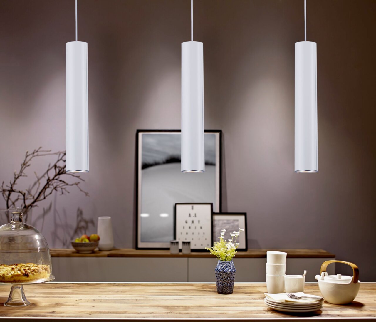 PAULMANN Schienenpendel Catalejo URAIL Drei moderne, zylindrische Pendelleuchten in einem stilvoll eingerichteten Raum, von vorne betrachtet.