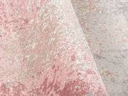 Nahaufnahme eines Designer-Teppichs mit rosa, beige und grauen Farbtönen in einer strukturierten, abstrakten Musterung, aus seitlicher Perspektive aufgenommen.