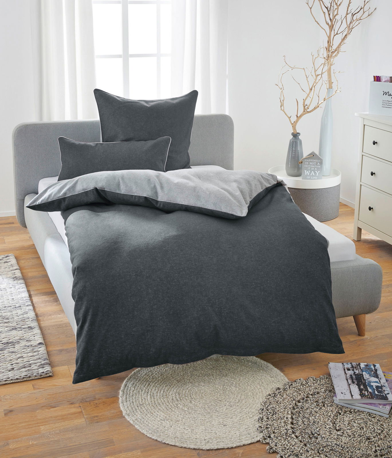 Bett mit grauer Melange-Flanell-Bettwäsche in einem hellen Schlafzimmer, Vorderansicht