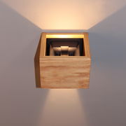 Moderne Wandleuchte aus Holz mit indirekter Beleuchtung, frontal betrachtet.