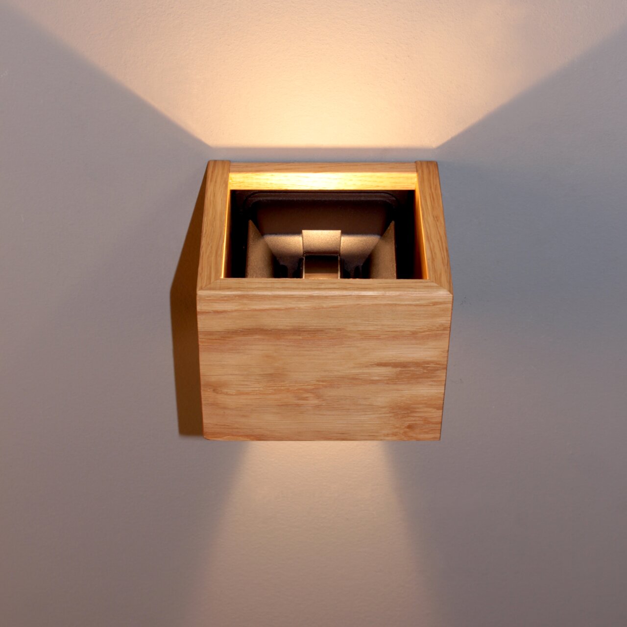 Moderne Wandleuchte aus Holz mit indirekter Beleuchtung, frontal betrachtet.
