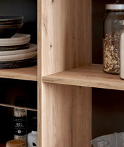 Nahaufnahme einer Kücheninsel mit Holzregalen, gefüllt mit Geschirr, Gewürzen und Vorratsgläsern, seitliche Perspektive.