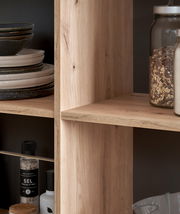 Nahaufnahme einer Kücheninsel mit Holzregalen, gefüllt mit Geschirr, Gewürzen und Vorratsgläsern, seitliche Perspektive.