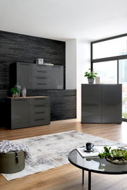 Moderne Wohnzimmermöbel in dunklem Grau, bestehend aus Kommode, Sideboard und Highboard, in einem stilvoll eingerichteten Raum mit Holzfußboden und großen Fenstern. Perspektive von vorne.