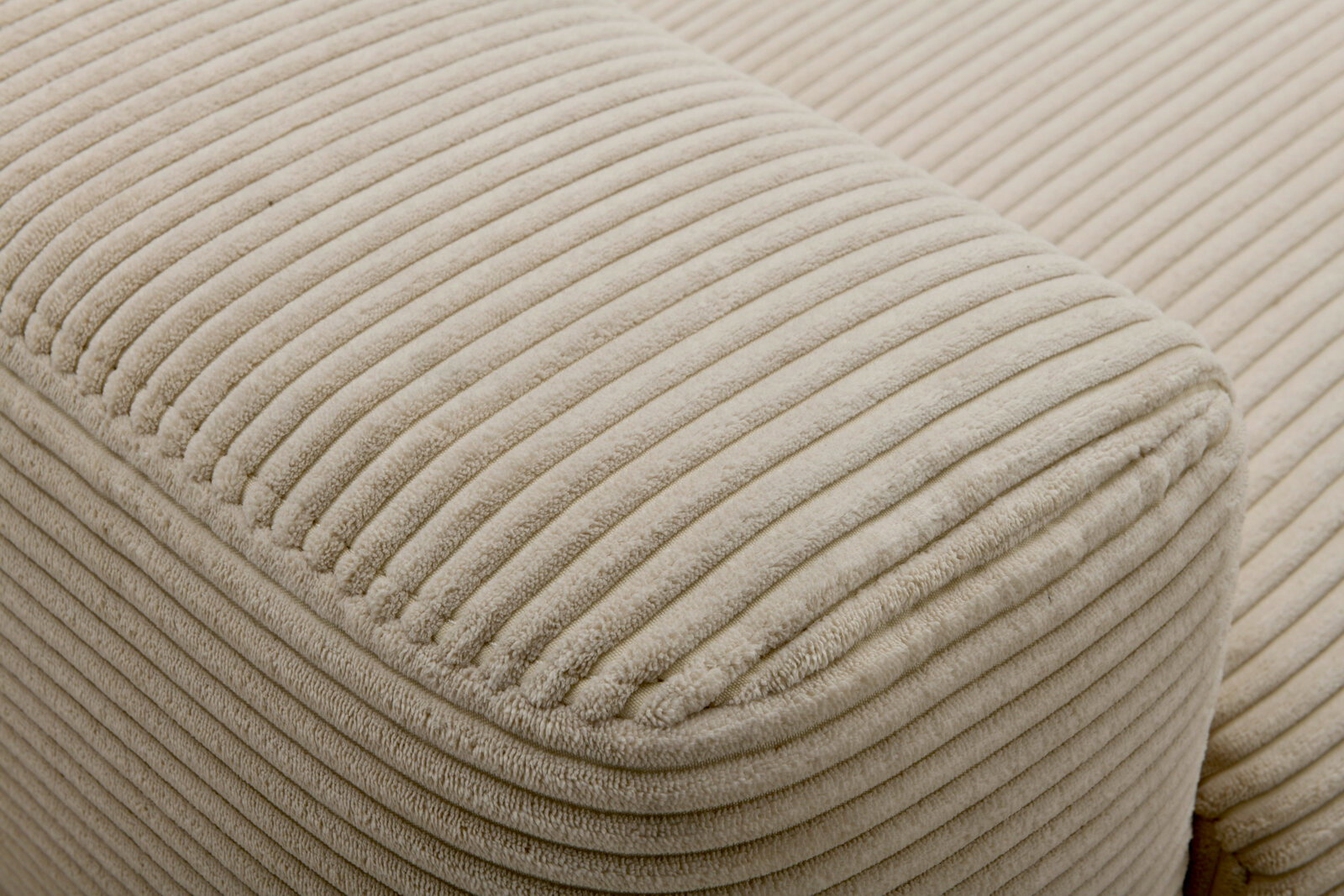 Nahaufnahme eines beigen, gerippten Stoffes eines Funktionssofas, seitliche Perspektive.