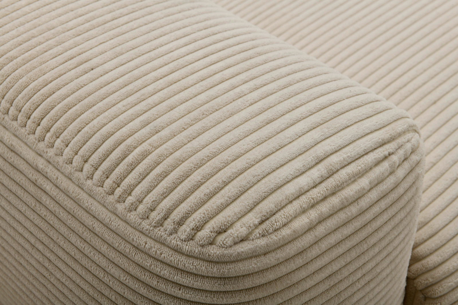 Nahaufnahme eines beigen, gerippten Stoffes eines Funktionssofas, seitliche Perspektive.