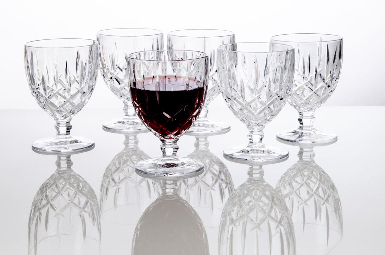 Sechs elegante Weinkelche Noblesse 350ml aus Kristallglas, einer davon mit Rotwein gefüllt, auf einer reflektierenden Oberfläche, seitliche Perspektive.