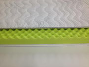 Kaltschaum-Topper SILVERCARE in seitlicher Perspektive, zeigt die wellenförmige Struktur des grünen Schaums und den weißen, gesteppten Bezug.