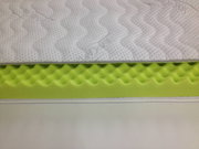 Kaltschaum-Topper SILVERCARE in seitlicher Perspektive, zeigt die wellenförmige Struktur des grünen Schaums und den weißen, gesteppten Bezug.