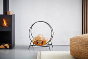 Moderner Kaminholzständer aus schwarzem Metall in einem Wohnzimmer, seitliche Perspektive.