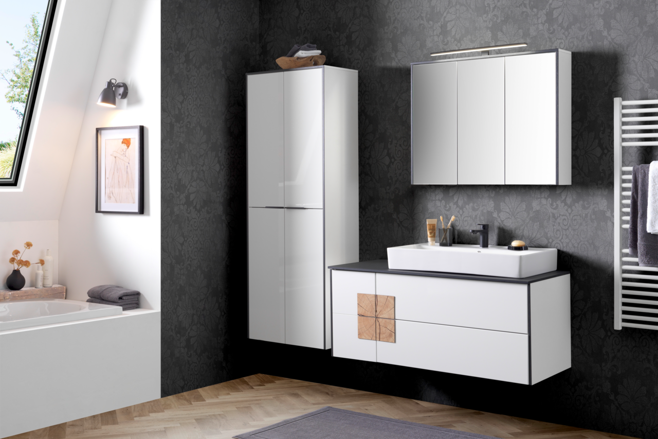 Modernes Waschtisch-Set in einem stilvollen Badezimmer mit dunkler Tapete, bestehend aus einem weißen Waschtisch mit schwarzer Ablagefläche, einem großen Spiegel und einem hohen Schrank. Perspektive: Frontalansicht.