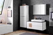 Modernes Waschtisch-Set in einem stilvollen Badezimmer mit dunkler Tapete, bestehend aus einem weißen Waschtisch mit schwarzer Ablagefläche, einem großen Spiegel und einem hohen Schrank. Perspektive: Frontalansicht.
