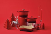 Runder roter Bräter in festlicher Dekoration mit Kerzen und Weihnachtsbaum, seitliche Perspektive