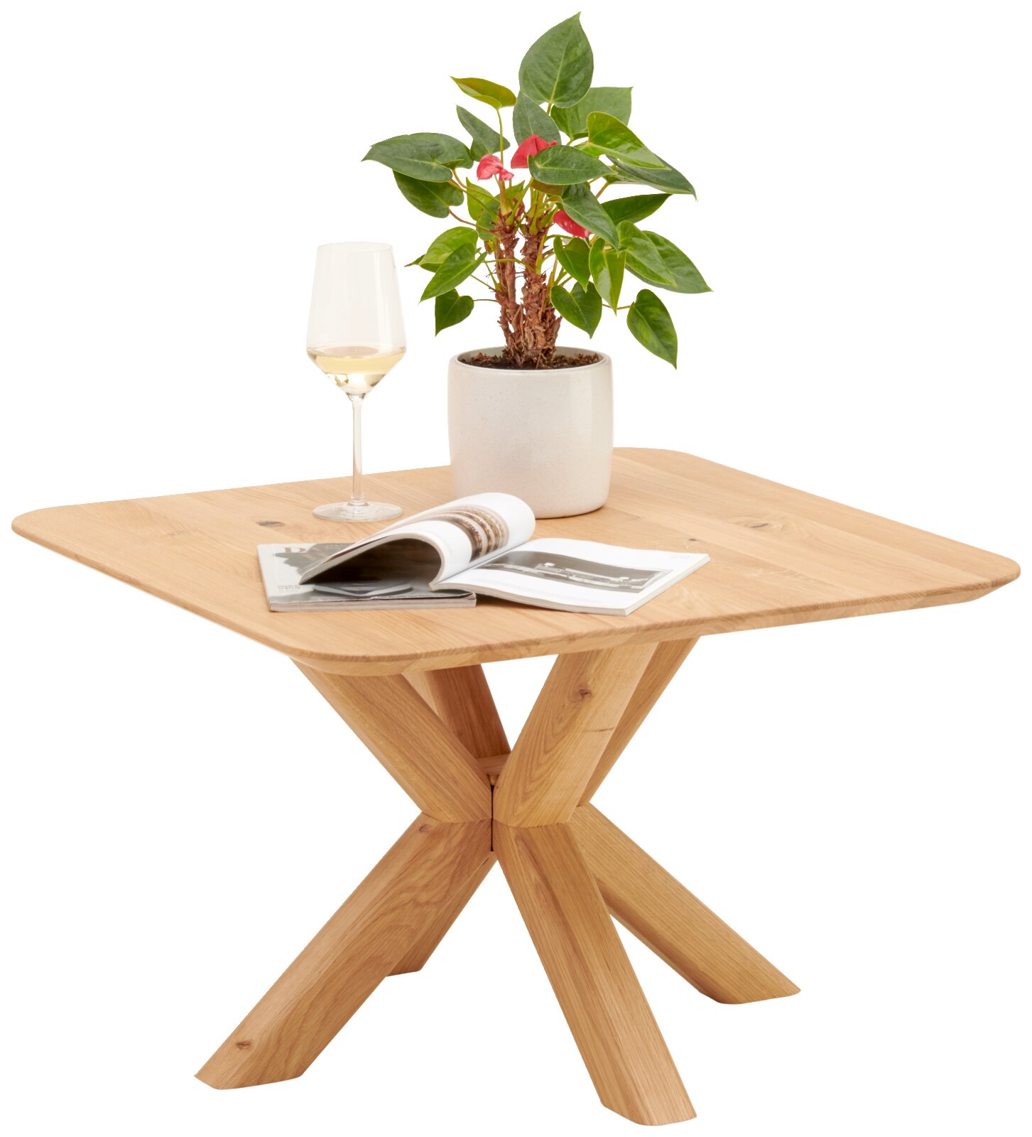 Beistelltisch aus Holz mit X-förmigem Gestell, darauf ein Weinglas, eine Pflanze im Topf und ein aufgeschlagenes Magazin, seitliche Perspektive