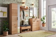 Moderne Garderobeneinrichtung aus Holz mit Schuhschrank, Spiegel, Garderobenbank und Hakenleiste in einem hellen Raum mit Pflanzen, aus frontaler Perspektive.
