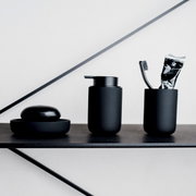 Schwarzes Badezimmer-Set bestehend aus Seifenschale, Seifenspender und Zahnputzbecher mit Zahnbürste und Zahnpasta, seitliche Perspektive.
