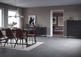 Moderner Essbereich mit einem schwarzen Tisch und weinroten Stühlen, im Hintergrund ein Couchtisch in einem stilvollen Wohnzimmer, seitliche Perspektive.