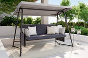Hollywoodschaukel mit grauem Gestell und Dach, seitliche Perspektive, umgeben von grünen Pflanzen auf einer Terrasse.