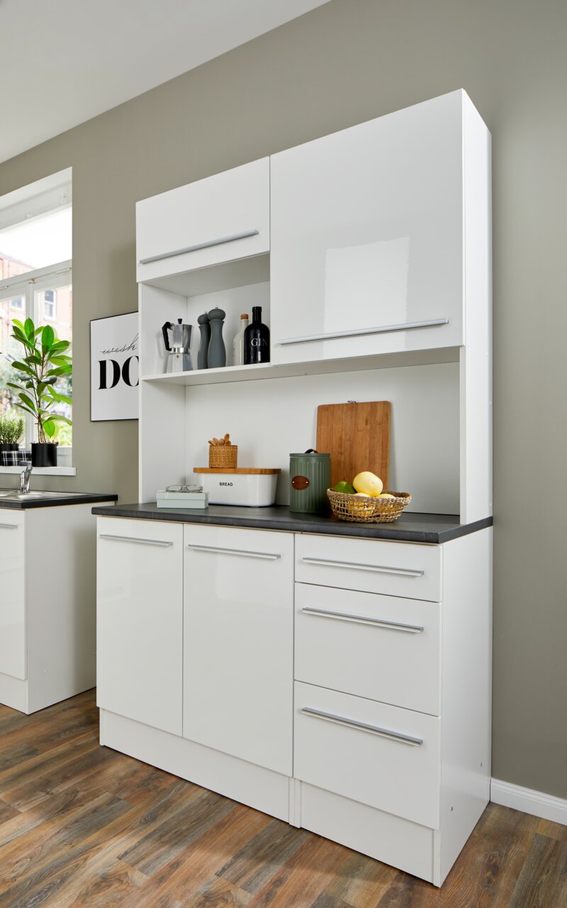 Moderner weißer Buffet-Schrank mit glänzender Oberfläche, mehreren Schubladen und Fächern, gefüllt mit Küchenutensilien, aus seitlicher Perspektive fotografiert.