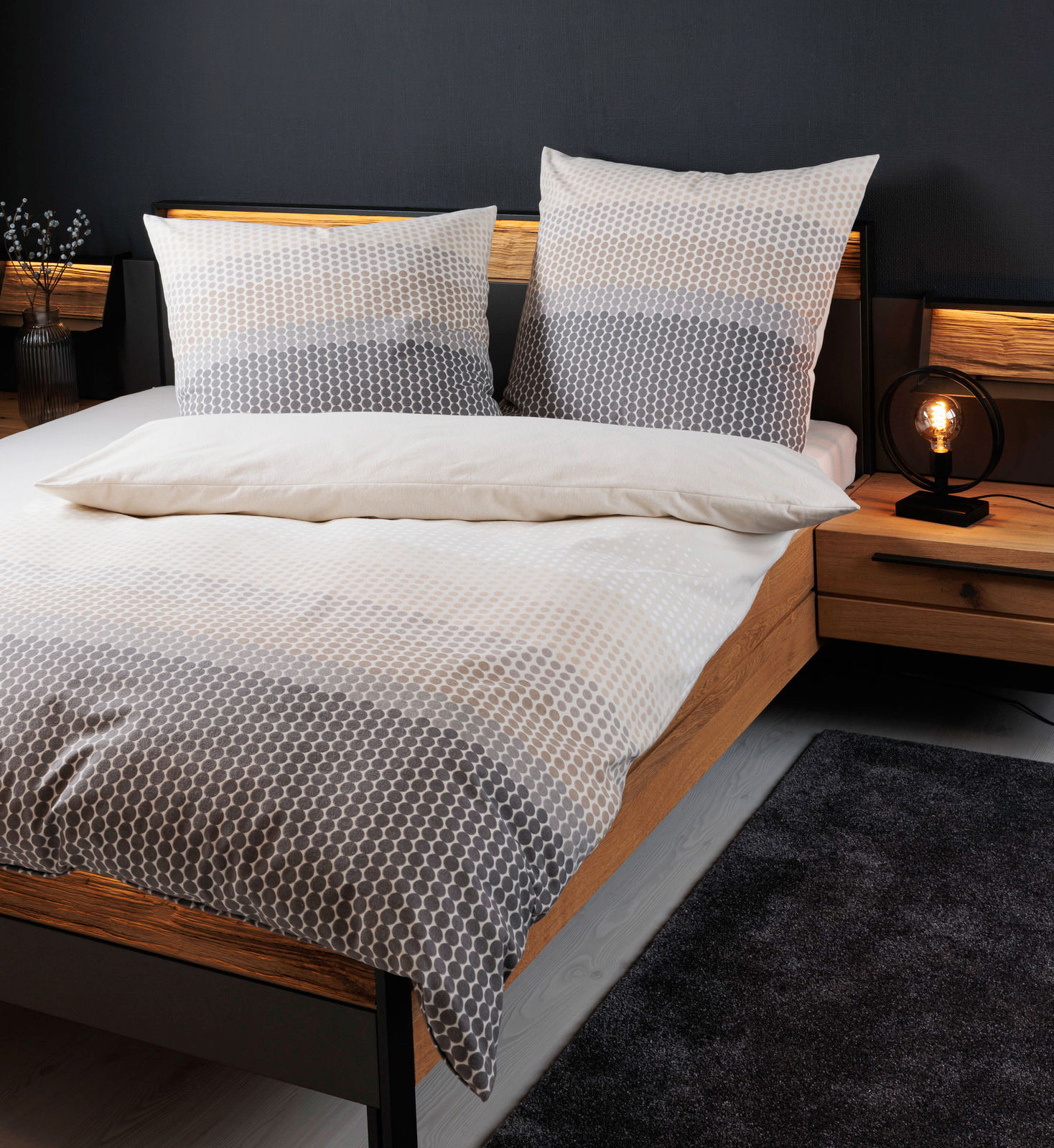 Bettwäsche-Set in Grau- und Beigetönen mit geometrischem Muster auf einem Holzrahmenbett, seitliche Perspektive