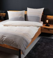 Bettwäsche-Set in Grau- und Beigetönen mit geometrischem Muster auf einem Holzrahmenbett, seitliche Perspektive