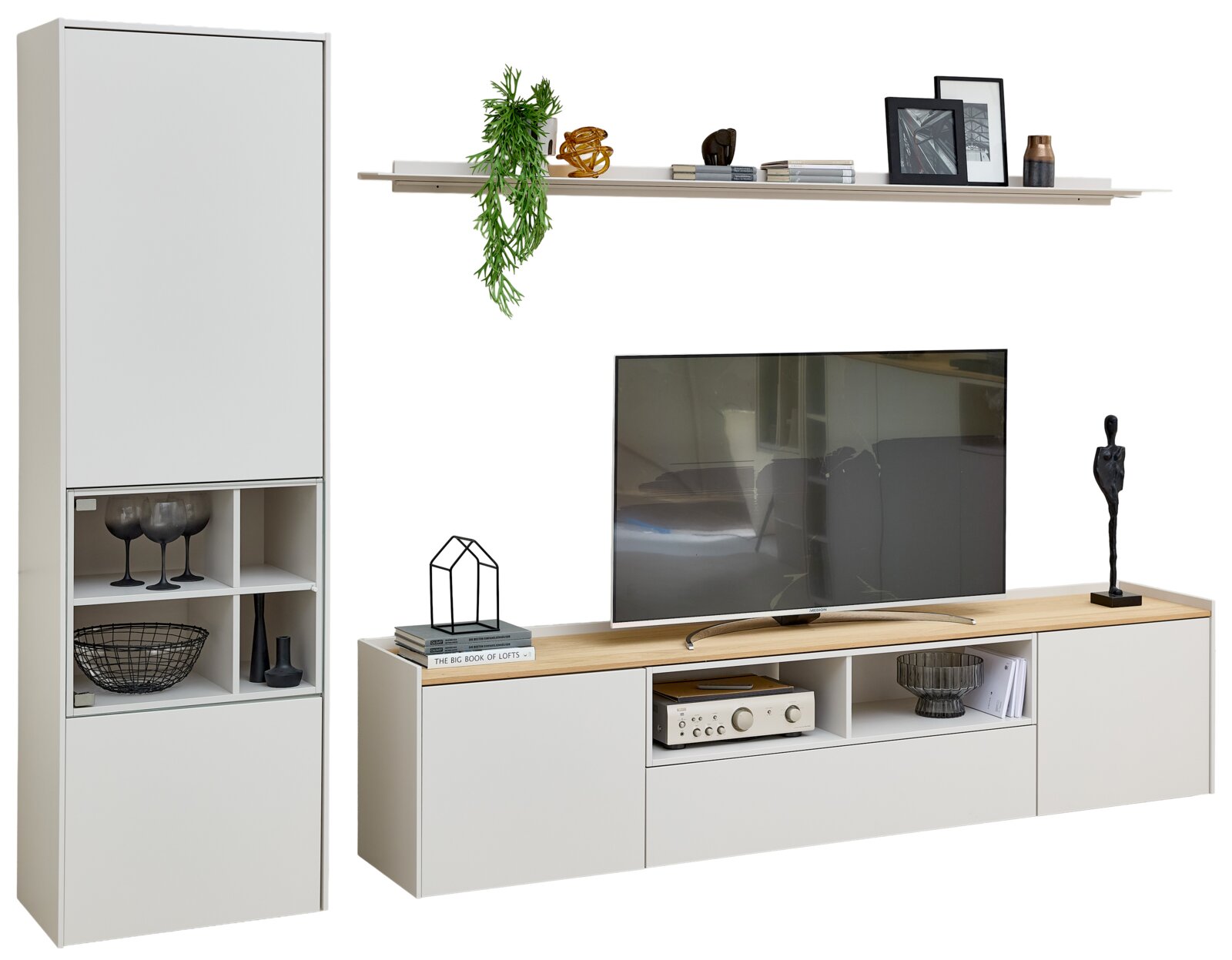 Moderne witte tv-wandkast met hoge vitrinekast, zwevend wandrek en laag tv-meubel met houtkleurig blad, gestyled met decoratie en weergegeven vanuit schuin vooraanzicht.