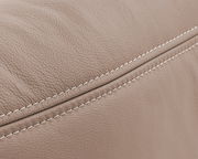 Nahaufnahme einer beigen, strukturierten Lederoberfläche mit sichtbaren Nähten, perspektivisch von der Seite aufgenommen.