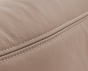 Nahaufnahme einer beigen, strukturierten Lederoberfläche mit sichtbaren Nähten, perspektivisch von der Seite aufgenommen.