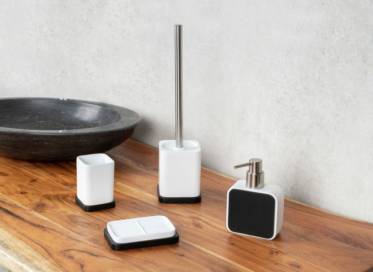 Badezimmer-Set Amara in Weiß und Schwarz, bestehend aus Seifenschale, Seifenspender, WC-Bürste und Aufbewahrungsbecher, auf einer Holzoberfläche von vorne fotografiert.