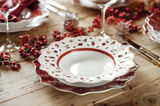 Suppenteller mit weihnachtlichem Design, von oben fotografiert, auf einem festlich gedeckten Tisch mit roten Beeren und Besteck.