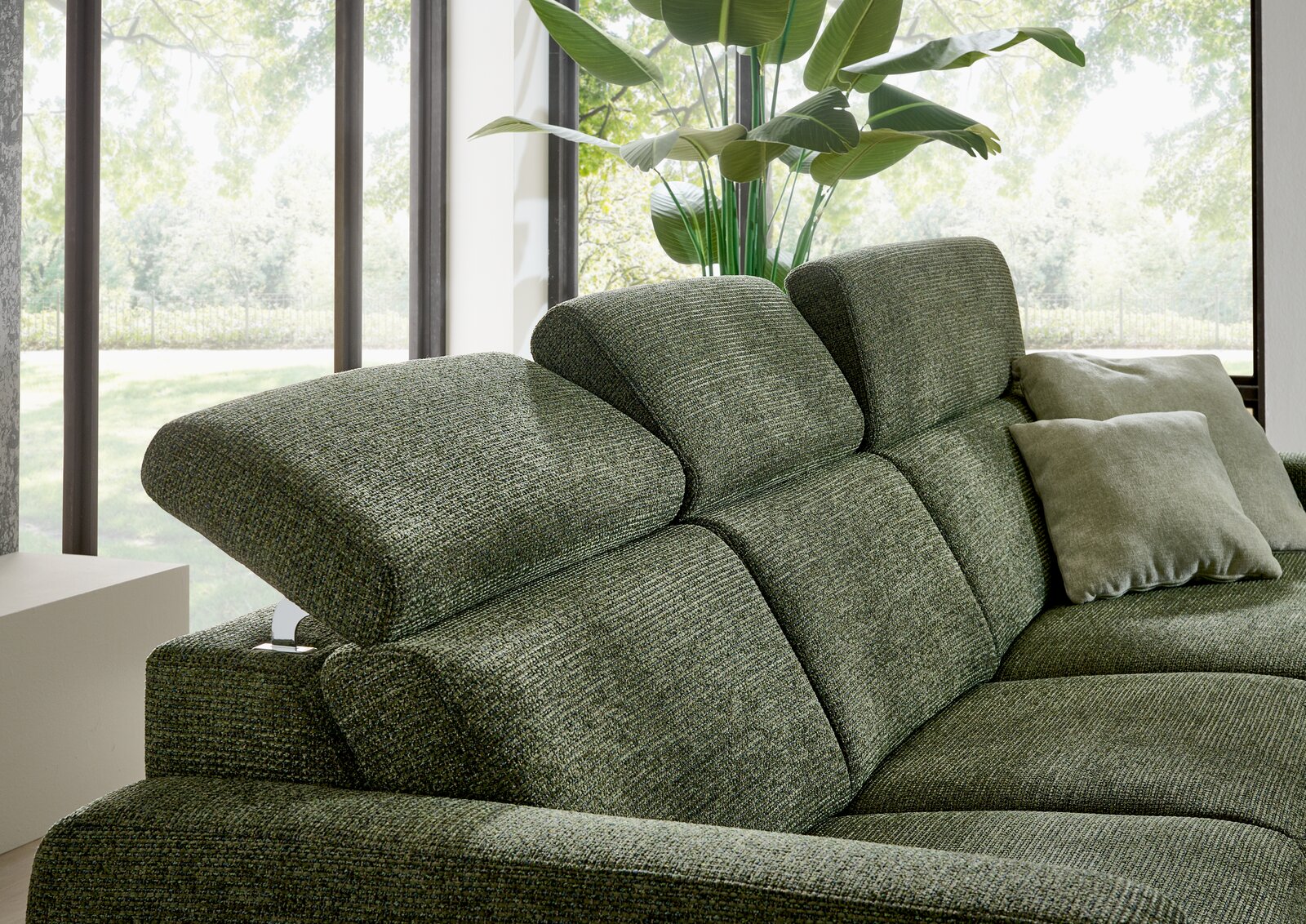 Grüne Longchairkombination mit verstellbaren Kopfstützen, seitliche Perspektive, im Hintergrund große Fenster mit Blick ins Grüne.